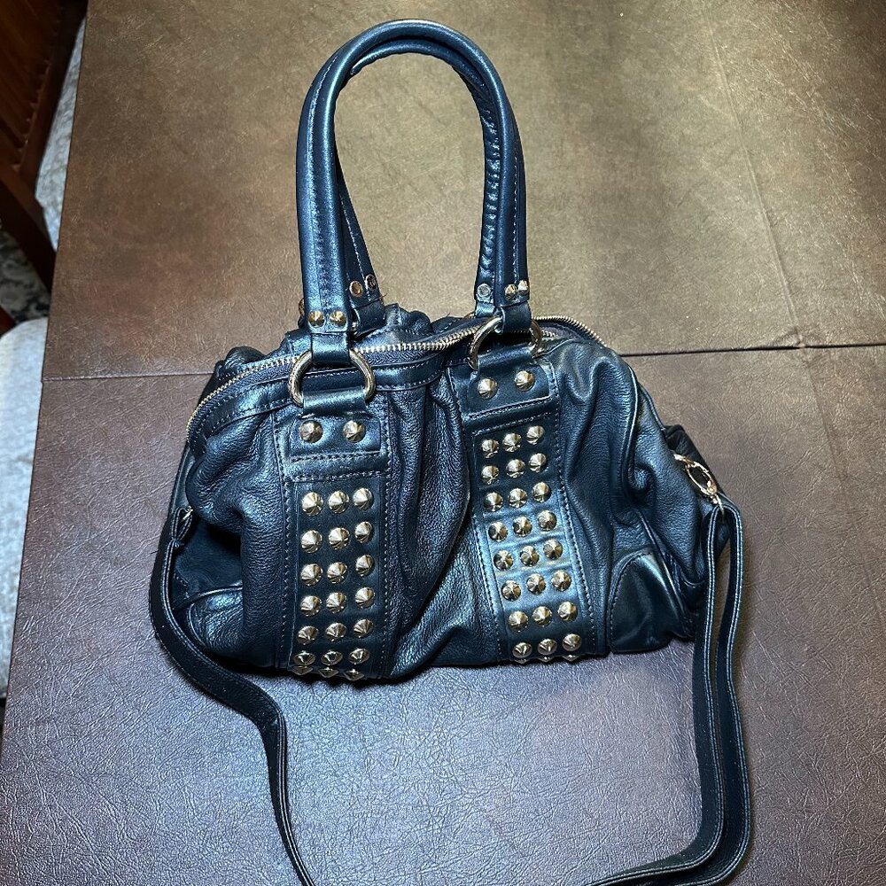 Black vegan leather satchel with top handles, gold rivets, and shoulder strap